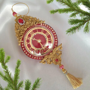 Handcrafted vintage-style red velvet clock Christmas ornament decorated with rhinestones and tassels on a Christmas tree